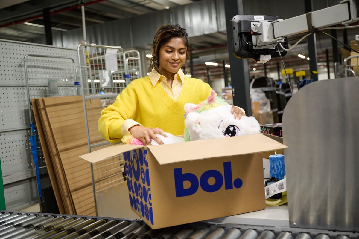 Een glimlachende man en vrouw staan in een magazijn vol dozen en pakt een doos uit.