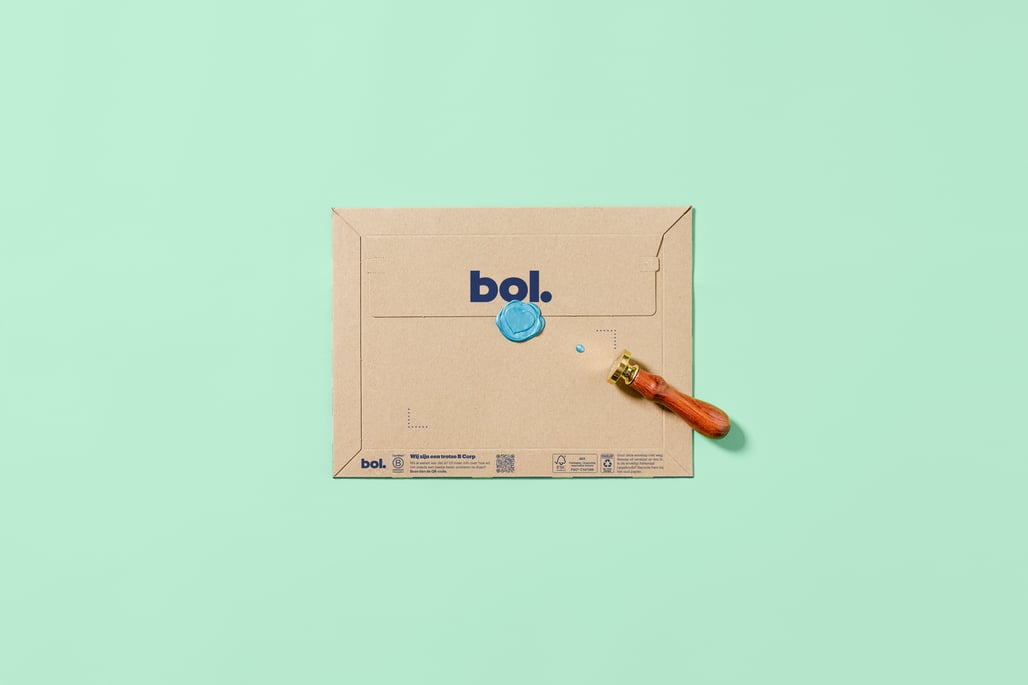 A decorative envelope with a blue circular pattern and a wax seal lies on a mint green background. A sealing stamp with a wooden handle is next to it.