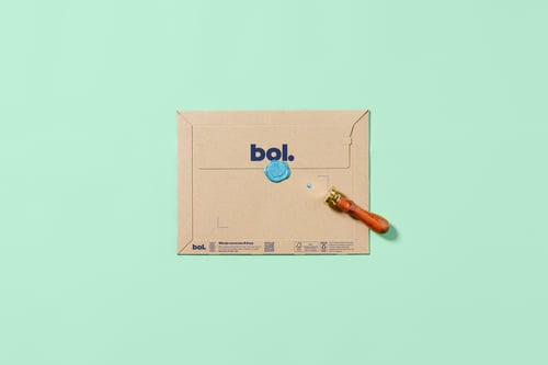 Een decoratieve envelop met een blauw cirkelvormig patroon en een lakzegel ligt op een mintgroene achtergrond. Een zegelstempel met een houten handvat bevindt zich ernaast.
