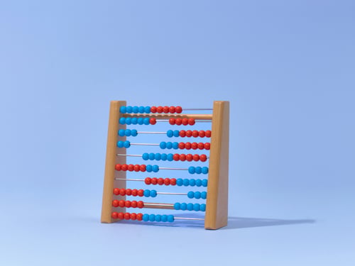 Houten telraam met rijen afwisselend rode en blauwe kralen, tegen een lichtblauwe achtergrond.