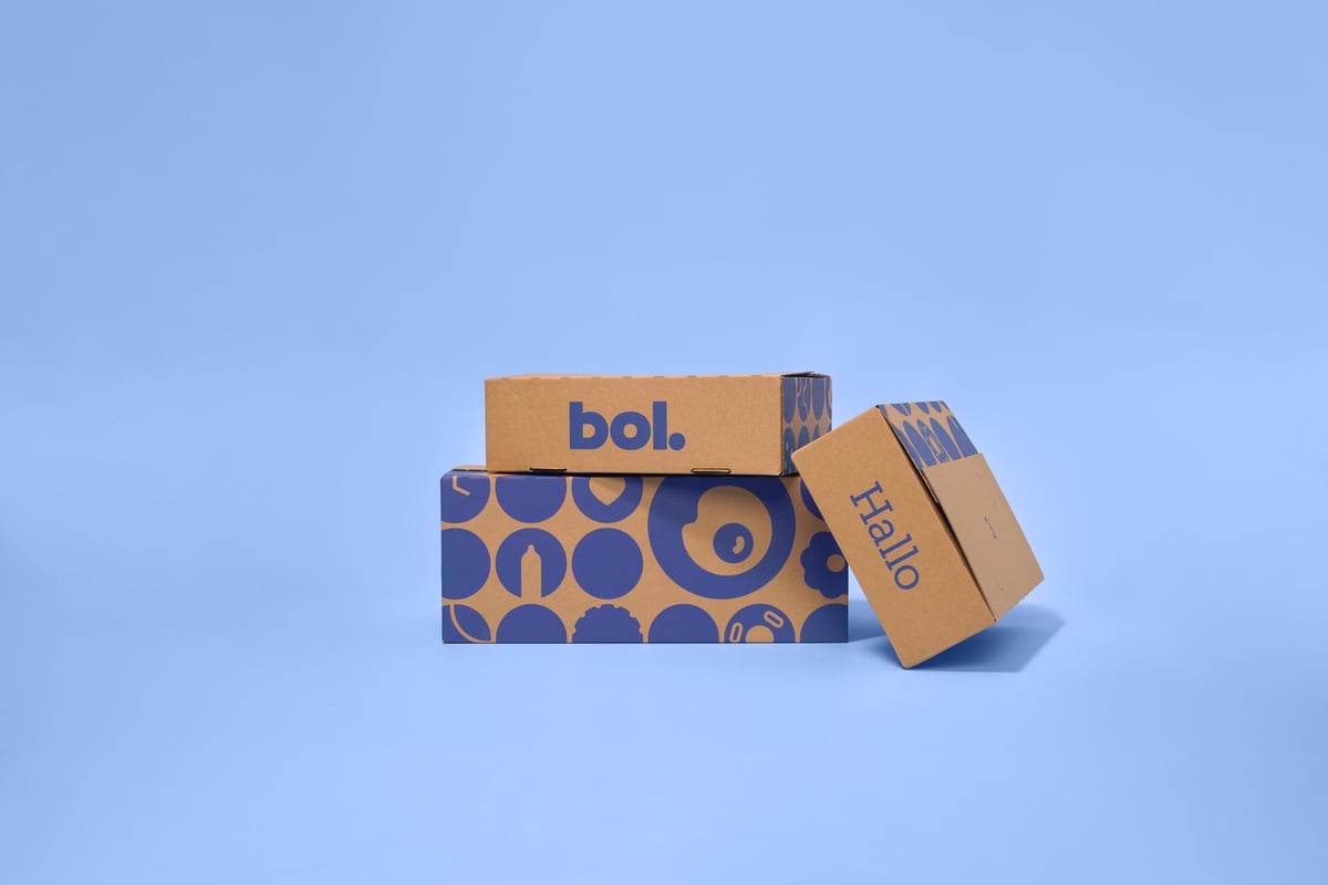 Three cardboard boxes on a light blue background. The boxes have blue patterns and text.