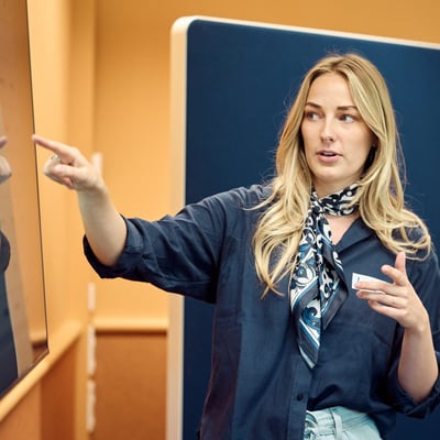 A woman pointing to a whiteboard.
