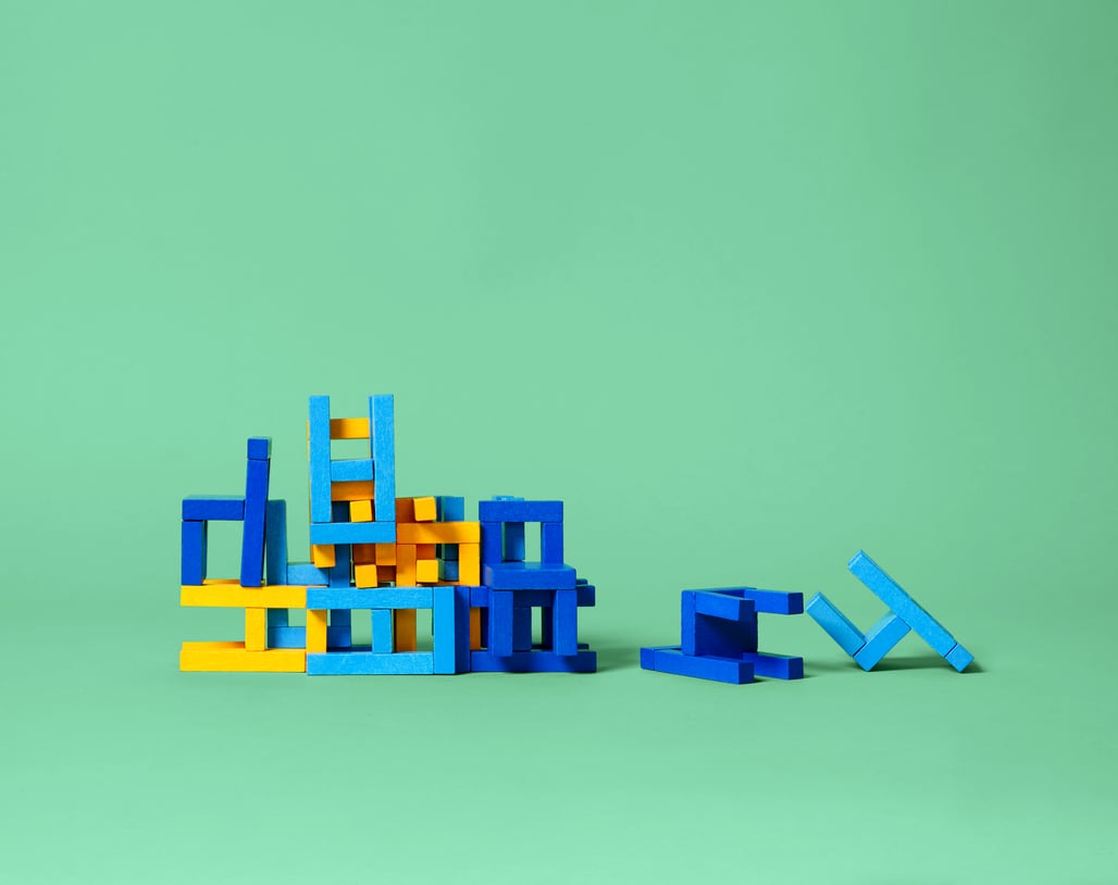 Kleurrijke houten blokken in verschillende tinten blauw en geel zijn gestapeld op een mintgroene achtergrond. 