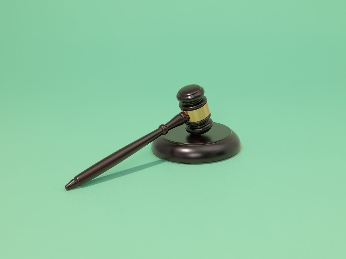 Wooden gavel with striking block on a green background.
