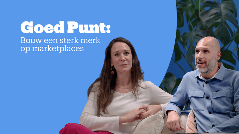 Twee mensen zitten voor een blauwe achtergrond met grote groene planten.
