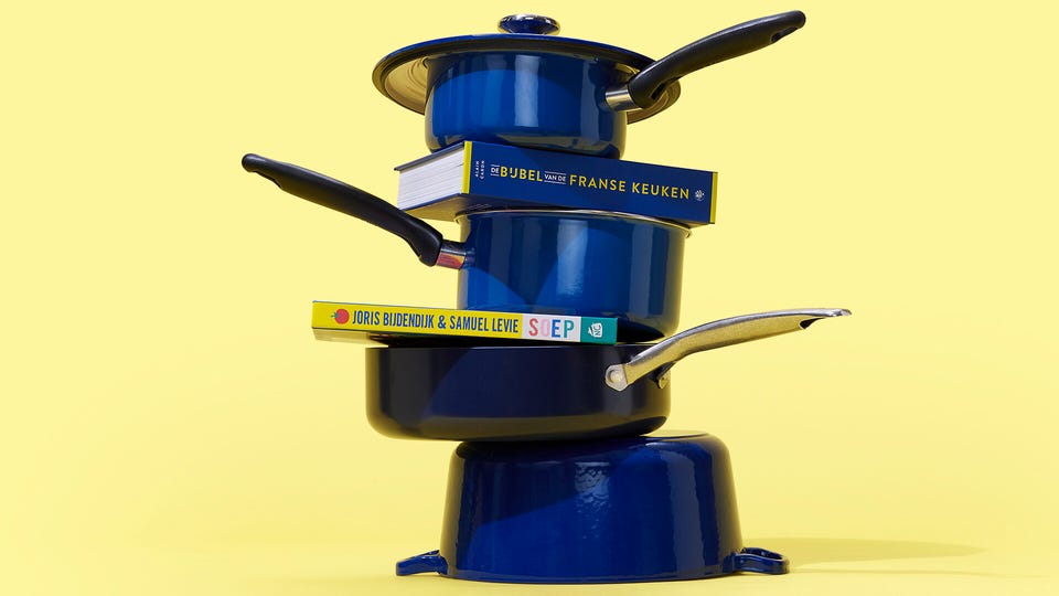 Stapel van blauwe pannen met daartussenin kookboeken