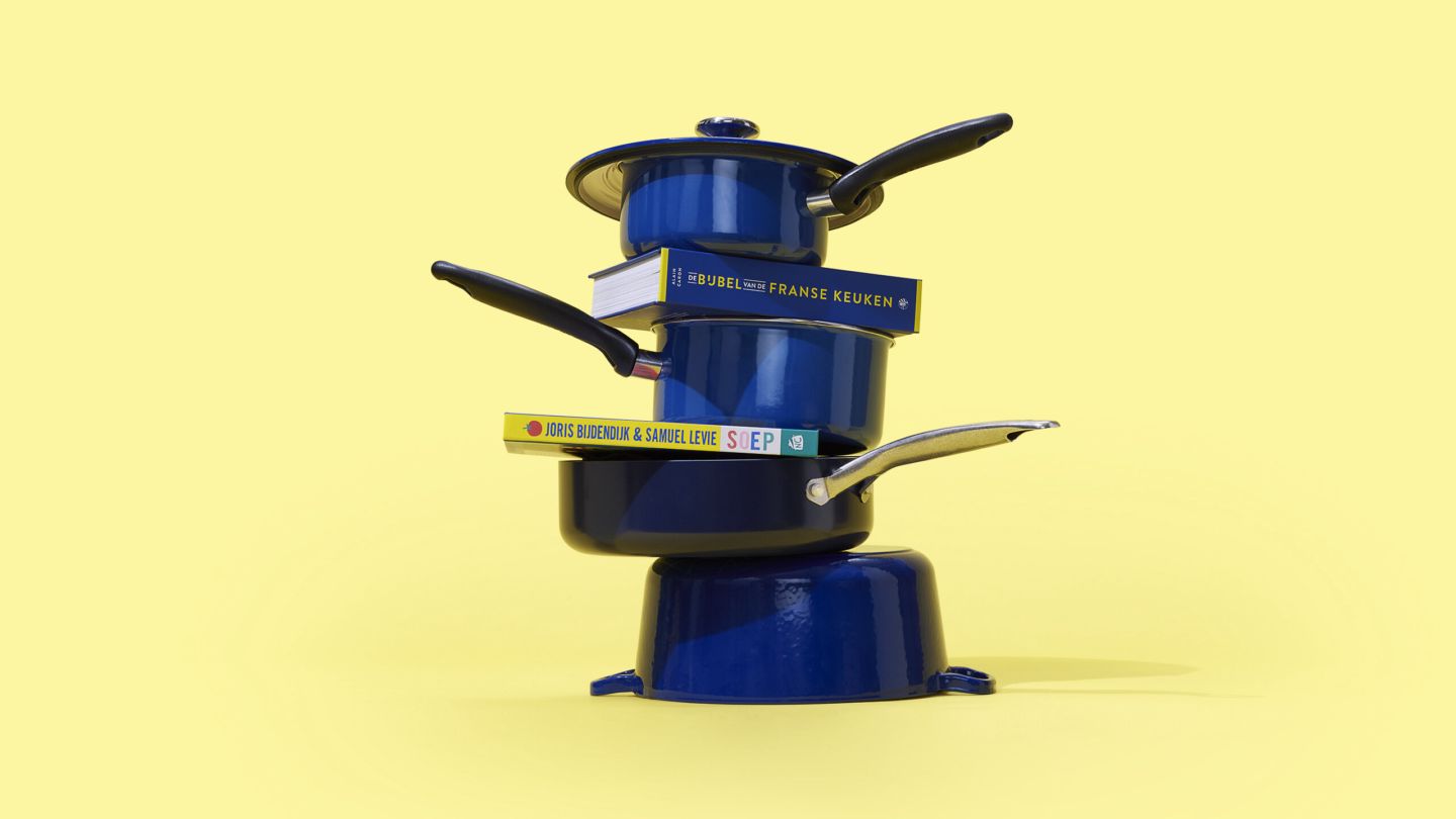 Stapel van blauwe pannen met daartussenin kookboeken