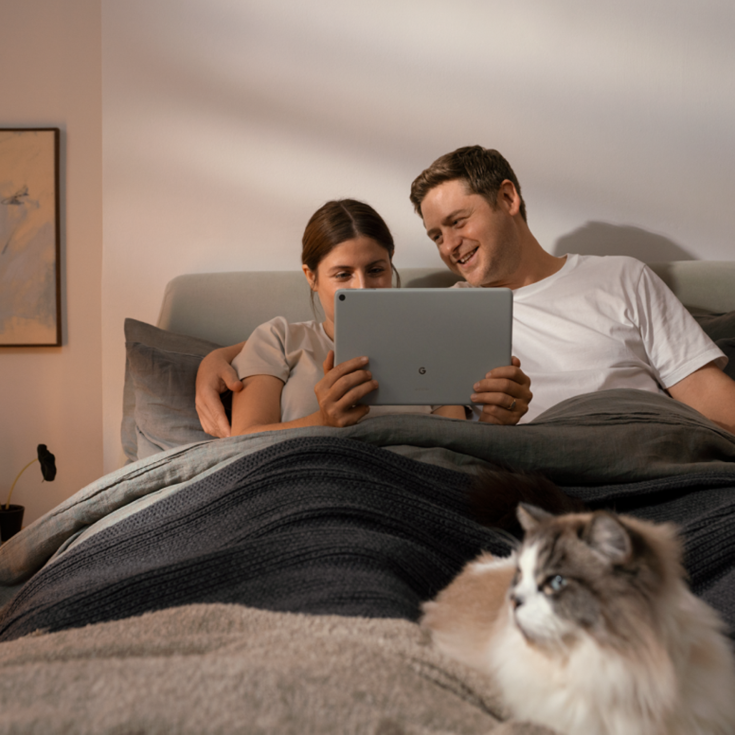 Een vrouw en een man die de Google Pixel Tablet in bed gebruiken.png