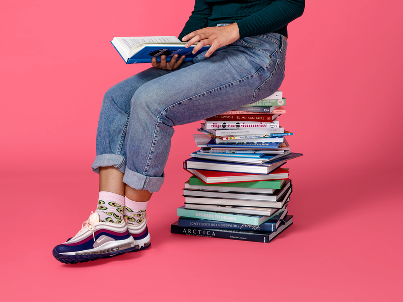 Persoon op boekenstapel met boek in hand