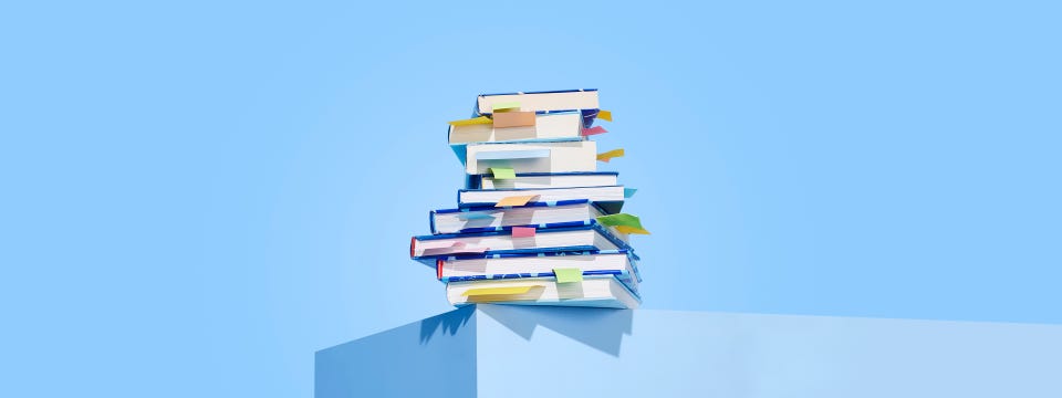 Persoon op boekenstapel met boek in hand